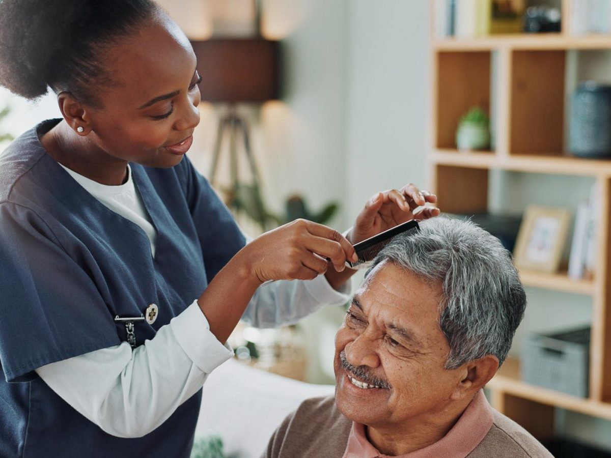 Carer grooming older mans hair after washing